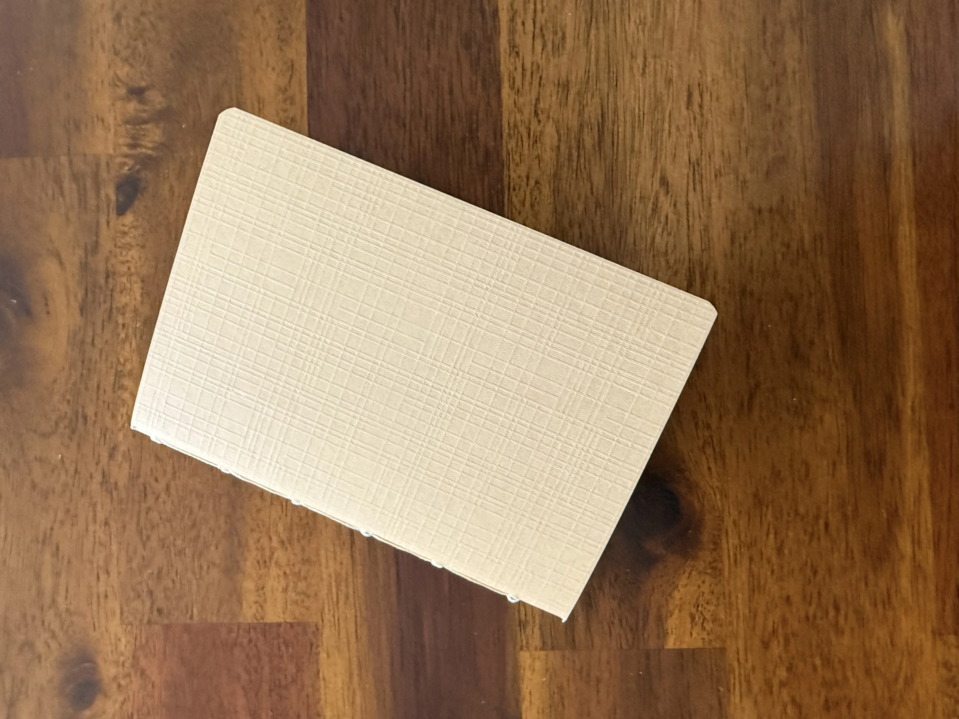 Cream textured passport notebook resting on a wooden table