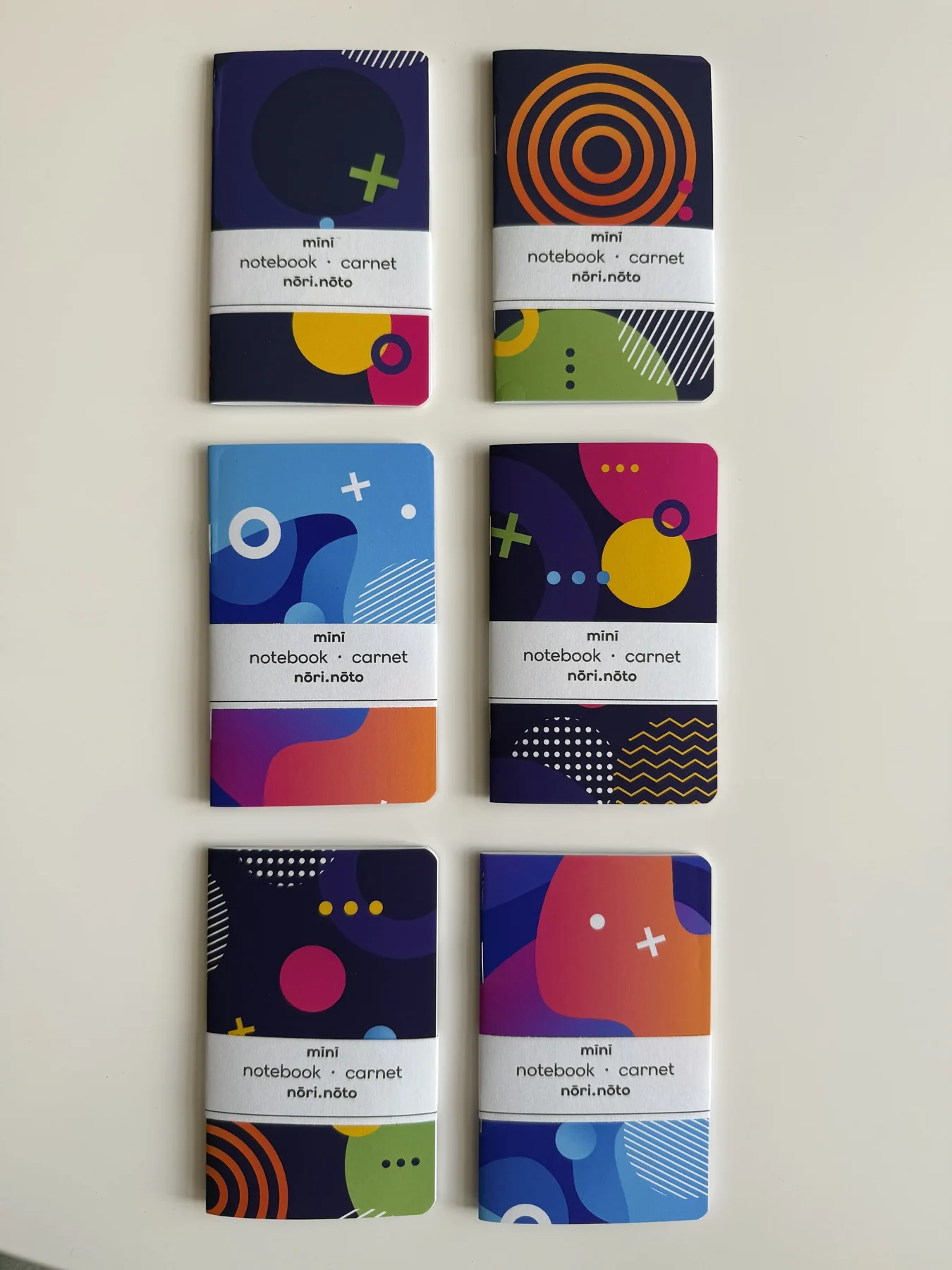 A collection of handmade Mīnī Fankī notebooks with vivid abstract covers