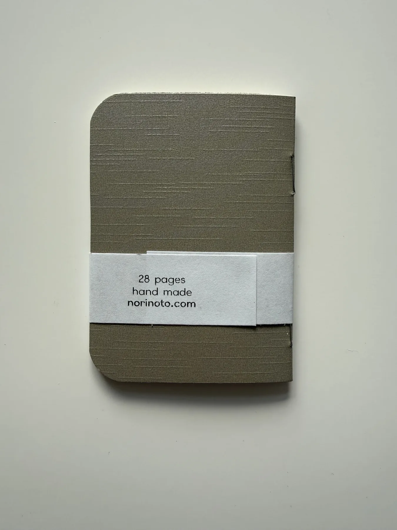 Back of the olive Mīnī notebook showing its handmade label