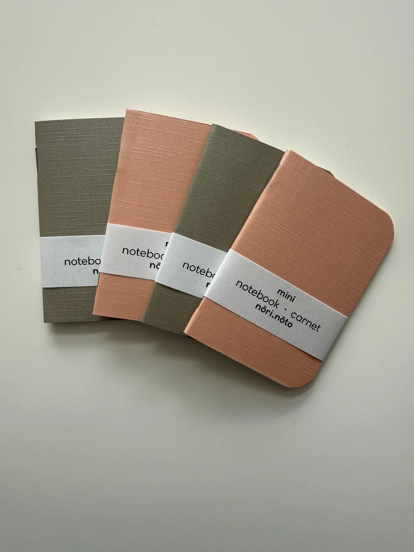Four Mīnī notebooks arranged in olive and coral