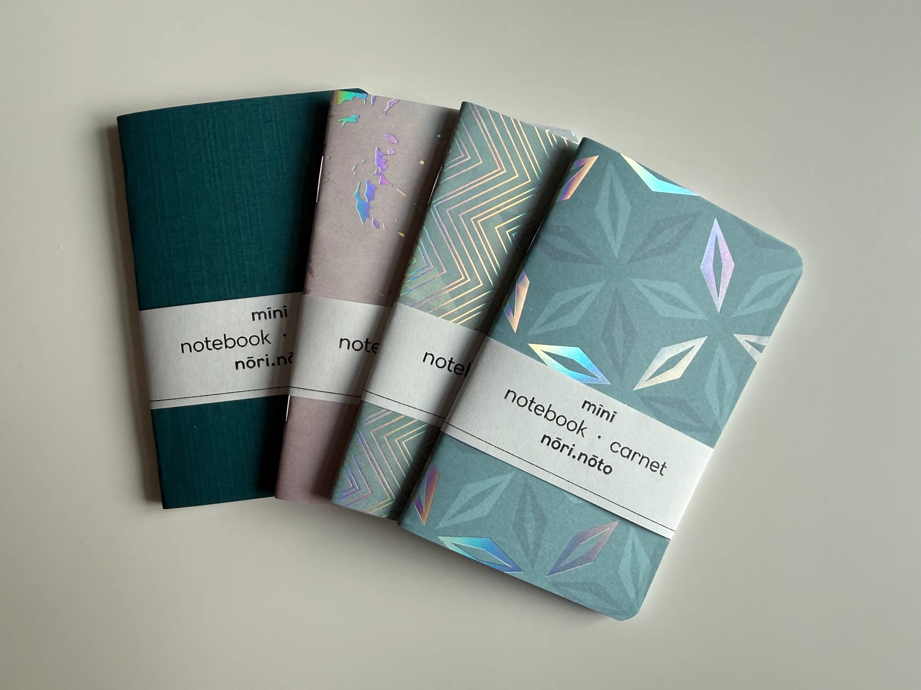 Five Mīnī notebooks arranged to show their patterned and textured covers