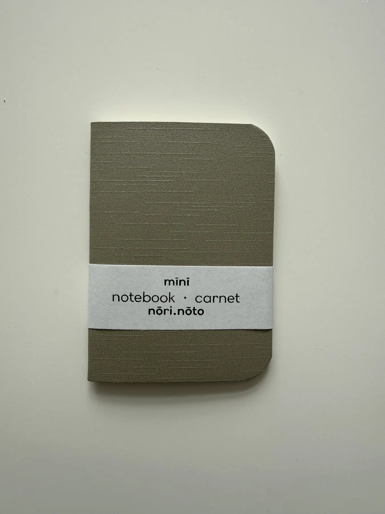 Olive Mīnī notebook with its paper band