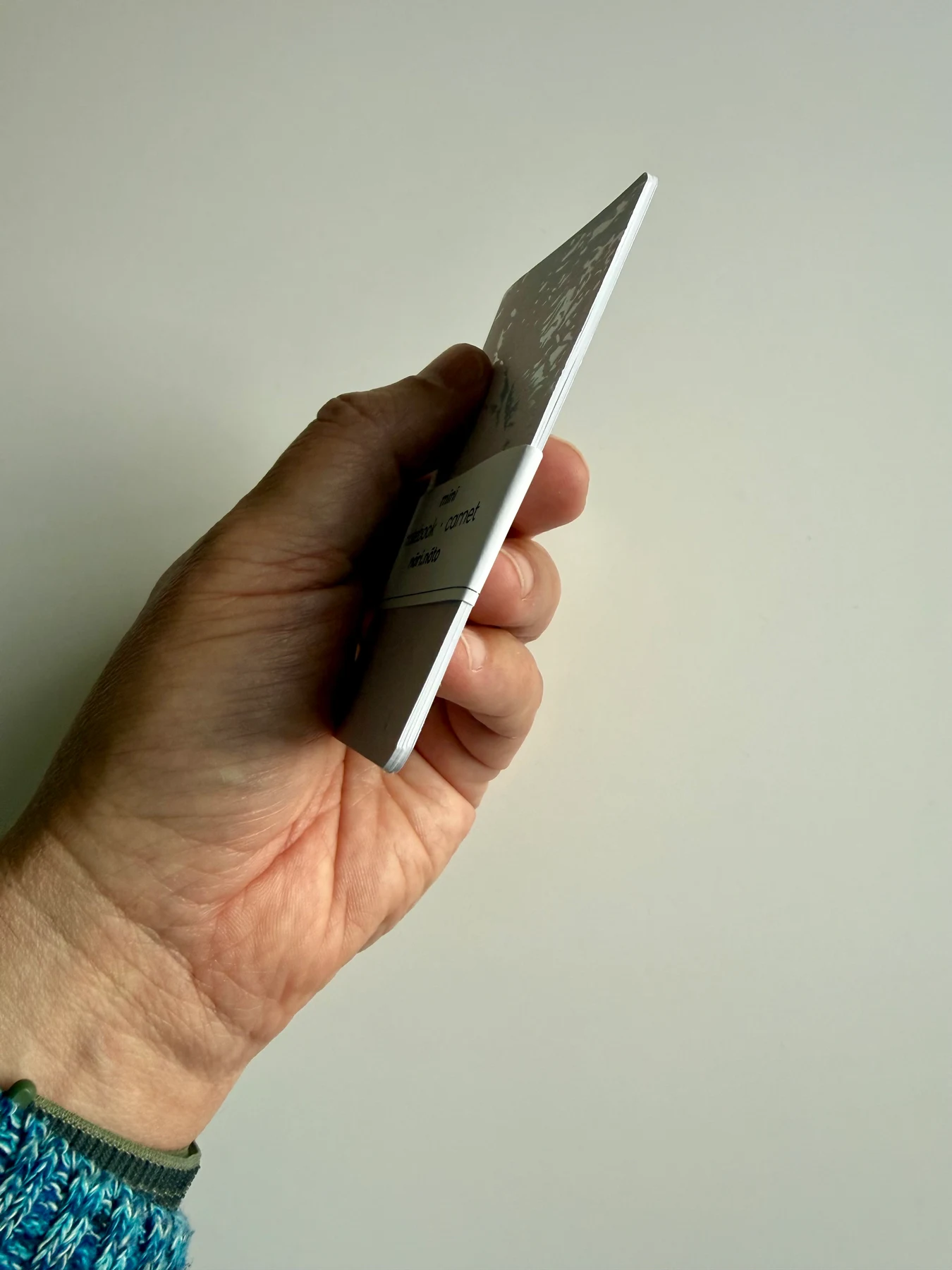 Side profile showing the slim Mīnī notebook and its pages