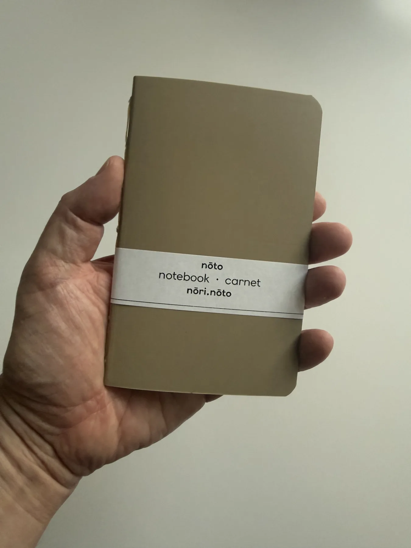 Brown-paper Nōto notebook held in one hand